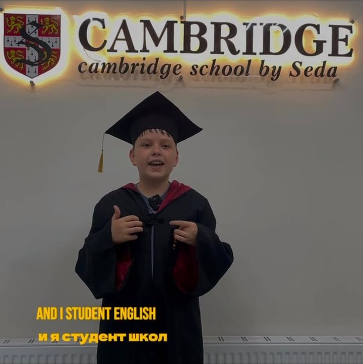 Ученик в мантии выпускника у вывески Cambridge School by Seda